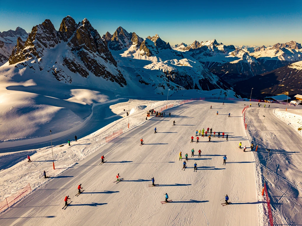 Luchtfoto van besneeuwde skipistes in Neustift im Stubaital met kleurrijke skigroepen op verschillende hellingen