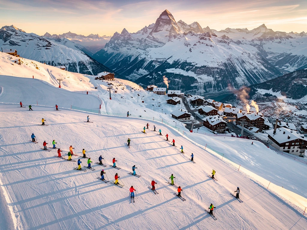 Ski instructors teaching groups on groomed Alpine slopes in Argentière with Mont Blanc massif backdrop during golden hour