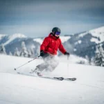 Beginner skiër op verzorgde alpine piste in rood jack, maakt onzekere bocht met skis naar buiten, verse sneeuw spat omhoog.