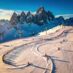 Aerial view of Kaprun ski slopes with colorful ski groups creating curved tracks in fresh snow, Austrian peaks in background
