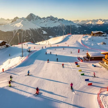 Luchtfoto van Königsleiten skipistes in ochtendlicht met skiërs op verschillende moeilijkheidsgraden en Oostenrijkse chalets