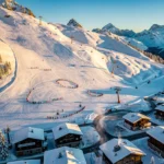 Luchtfoto van Les Carroz d'Arâches skigebied met besneeuwde Alpenhellingen, skiërs, chalets en liften bij gouden uur