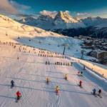 Luchtfoto van Les Deux Alpes skigebied met skipistes, skilessen en besneeuwde Alpentoppen in gouden ochtendlicht