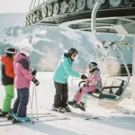Moniteur de ski aidant un débutant nerveux à monter sur un télésiège, groupe d'étudiants sur pistes enneigées