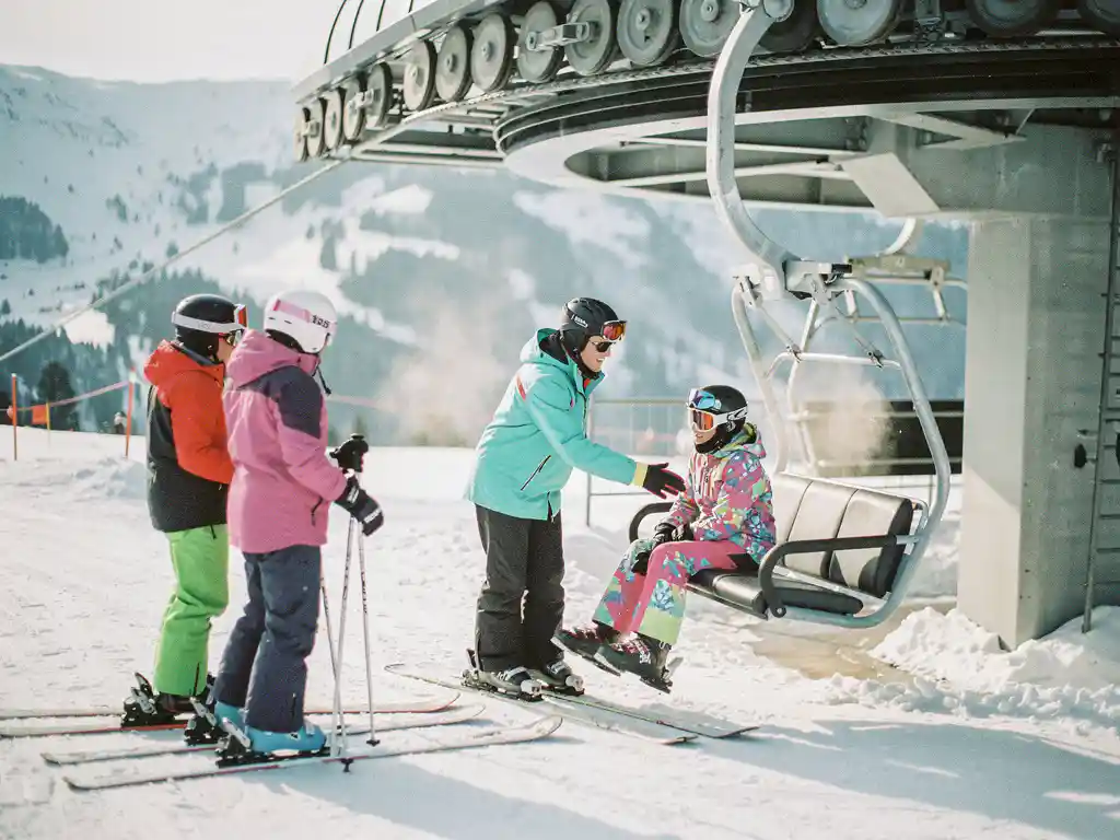 Moniteur de ski aidant un débutant nerveux à monter sur un télésiège, groupe d'étudiants sur pistes enneigées