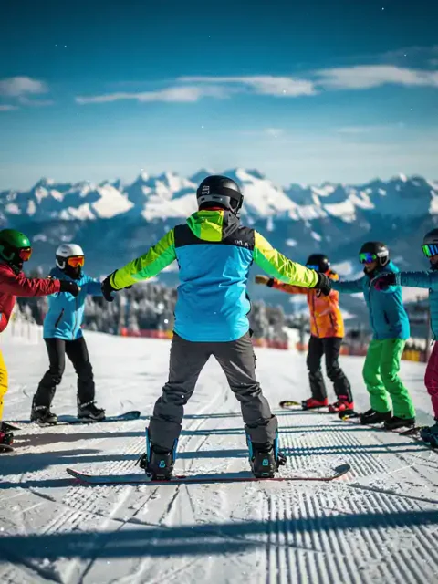 Moniteur de snowboard enseignant la posture correcte à des étudiants sur une pente de montagne enneigée