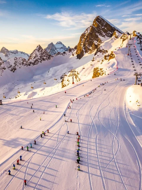 Luchtfoto van Obergurgl skipistes met skigroepen en instructeurs op verse poedersneeuw tijdens gouden uur