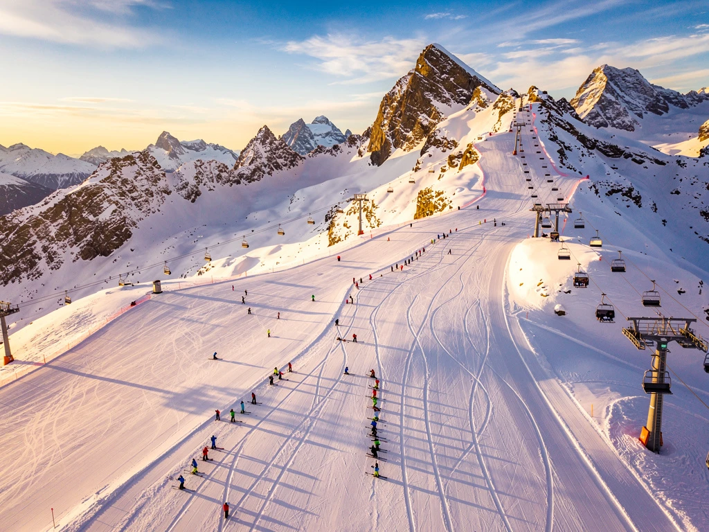 Luchtfoto van Obergurgl skipistes met skigroepen en instructeurs op verse poedersneeuw tijdens gouden uur
