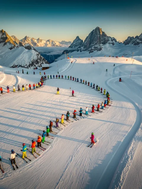 Ski instructors teaching groups on groomed slopes at Risoul resort during golden hour with Alpine peaks in background