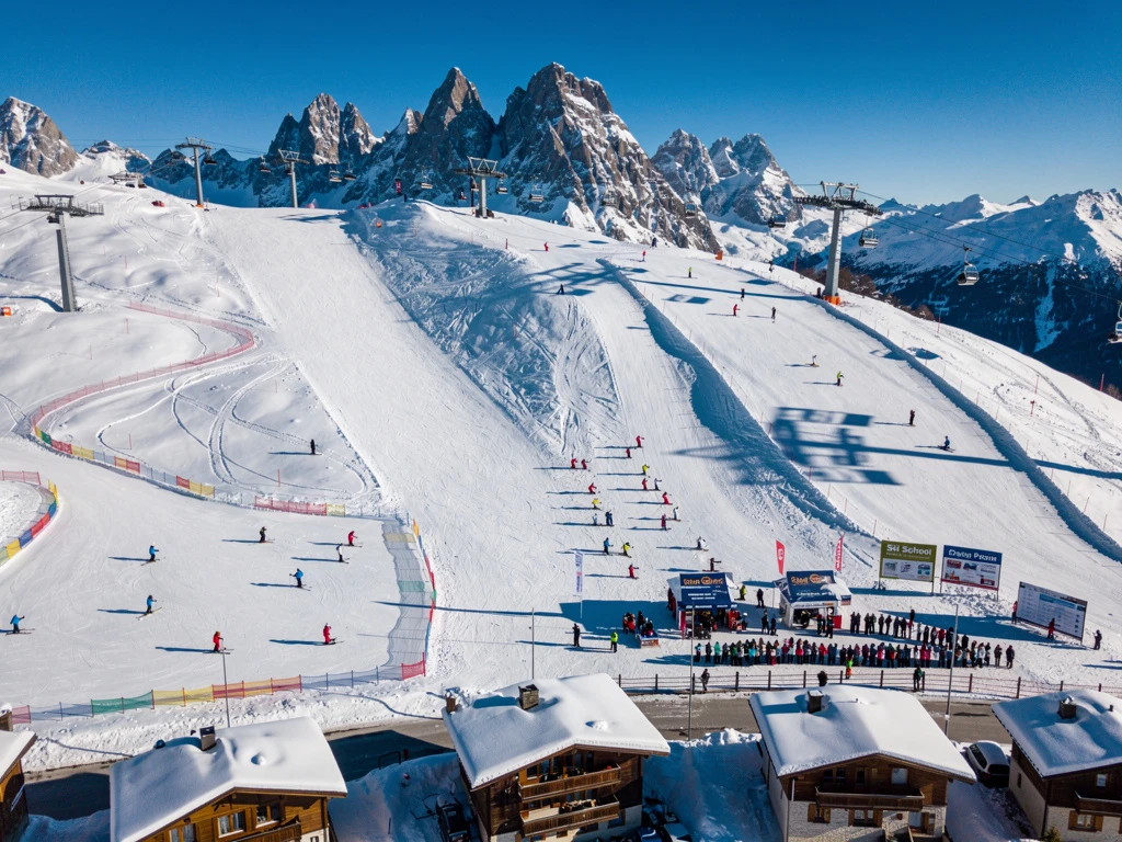 Aerial view of Samoëns ski resort in French Alps with ski instructors teaching groups on snowy slopes under blue skies