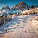 Aerial view of Sankt Gallenkirch Alpine ski slopes at golden hour with skiers on groomed runs and Austrian chalets below