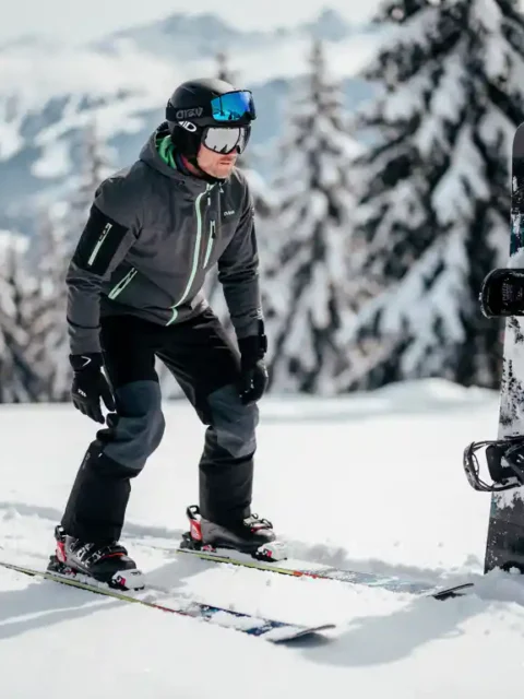Ski-instructeur toont juiste houding naast snowboard in sneeuw, winteruitrusting zichtbaar op bergpiste