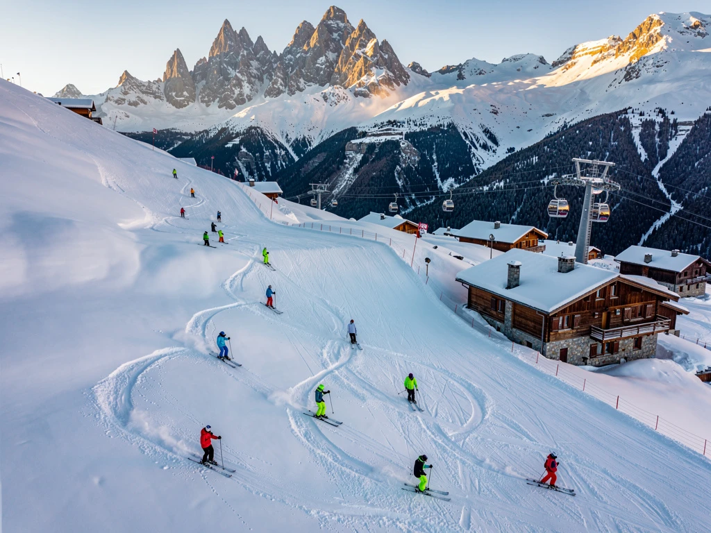 Ski instructors in bright jackets leading students down groomed Alpine slopes in Villard-Reculas with chalets and mountain peaks