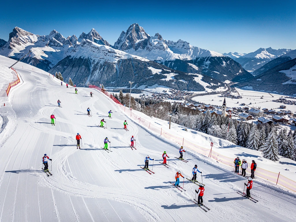 Aerial view of skiers on groomed slopes in Neustift im Stubaital with Stubai Alps and Austrian village below