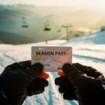 Snowboarder houdt seizoenskaart vast in handschoenen tegen verse poedersneeuw met skilift op achtergrond