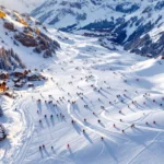 Luchtfoto van skihellingen St. Christoph am Arlberg bij zonsondergang met skileraren en leerlingen op besneeuwde pistes