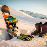 Snowboard mit Anfängerausrüstung auf frischem Pulverschnee, bunte Winterhelm, Skibrille und Handschuhe am Berghang