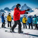 Snowboard-Lehrer in roter Jacke unterrichtet Schülergruppe auf sonnigem Berghang mit Alpenpanorama