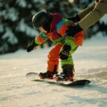 Beginnende snowboarder in kleurrijke winterkleding leert balanceren op besneeuwde helling met begeleiding van instructeur