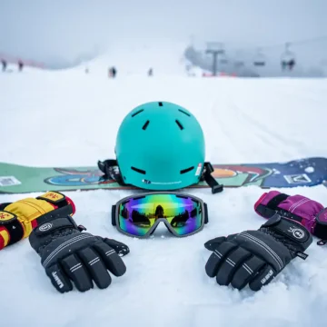 Snowboard uitrusting inclusief helm, handschoenen, polsbeschermers en skibril op verse poedersneeuw in skigebied