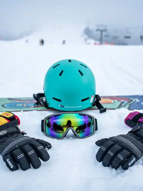Snowboard uitrusting inclusief helm, handschoenen, polsbeschermers en skibril op verse poedersneeuw in skigebied