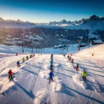 Aerial view of Val-d'Isère ski resort with multiple groups skiing down snow-covered slopes during golden hour lighting